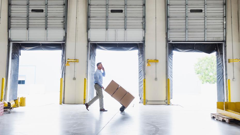 Man carrying out boxes inside a warehouse.