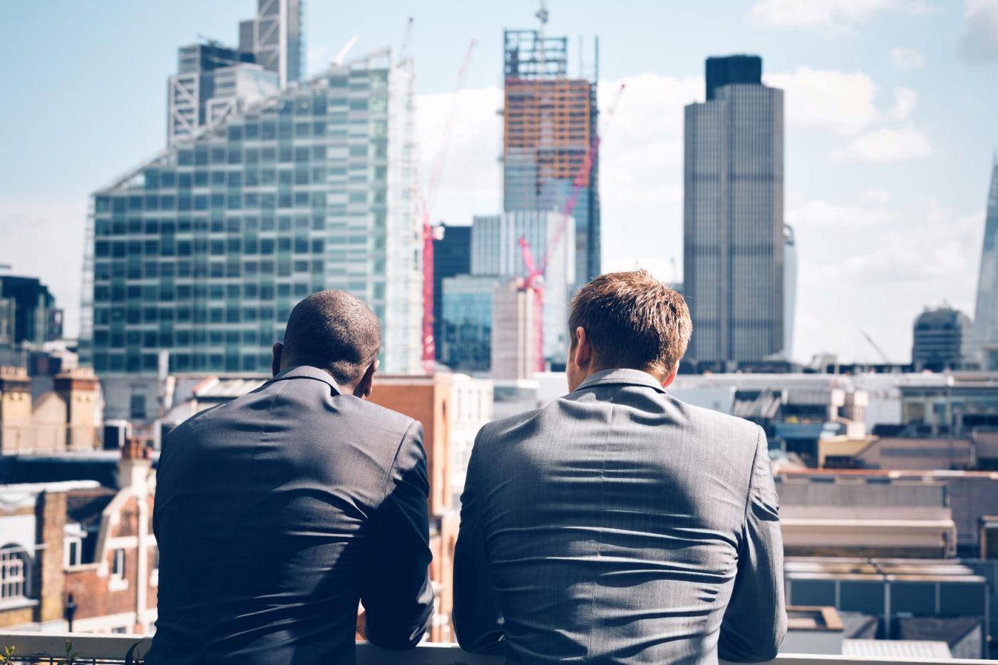 Two business men in balcony staring at the city.