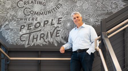 A person posing in front of a mural