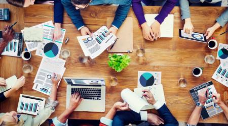 People sitting around a table with laptops and financial documents